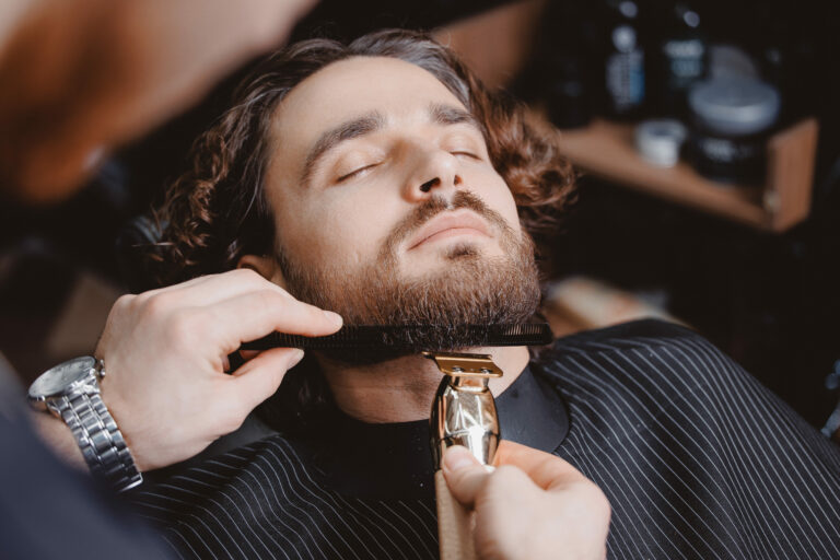 Homme sur un fauteuil de barbier en train de se faire tailler la barbe